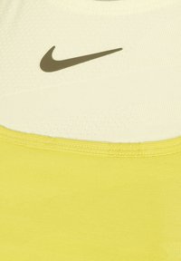 Top deportivo de Nike, con una base amarilla y un patrón texturizado, y una sección superior de color amarillo claro. Incluye un acento de logo oscuro.