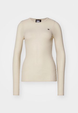 Kremowa koszula z długim rękawem, uszyta z miękkiego materiału, posiadająca okrągły dekolt i małe logo na lewej stronie klatki piersiowej.