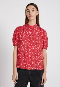 Blusa rossa a maniche corte con motivo floreale, dotata di colletto e maniche arricciate, realizzata in tessuto leggero.