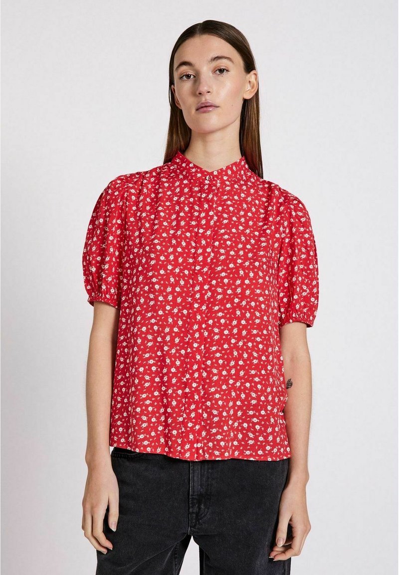 Blusa rossa a maniche corte con motivo floreale, dotata di colletto e maniche arricciate, realizzata in tessuto leggero.