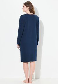 Mörkblå långärmad nattsär i mjukt tyg, knälång, med rund halsringning och kontrasterande kant samt en avslappnad passform.