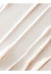 Glat hvid creme spredt i diagonale riller på en flad overflade, der viser tekstur og blødhed.