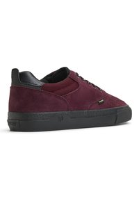 Burgundy suede sneaker with black accents, round toe, mesh panels, and black rubber sole. Features gold eyelets and logo detail on the heel.