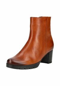 Bottine en cuir marron avec une texture lisse, un bout rond et un large talon noir, présentant des détails de couture minimalistes.