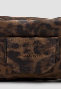Bolso de ante marrón con un patrón de leopardo, un bolsillo cosido y el detalle del logotipo en relieve "AllSaints". Textura suave en general.