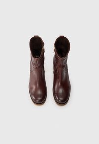 Bottines en cuir marron avec une finition lisse, un bout arrondi, des zips sur les côtés et des détails de couture subtils. Design classique avec une semelle en caoutchouc.