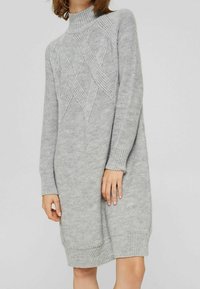 Robe pull grise tricotée avec un col montant, présentant un motif en losange texturé et des poignets et ourlet côtelés. Matière douce et confortable.