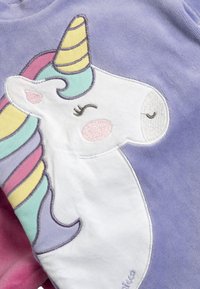 Tissu violet avec un design de licorne blanche présentant un visage brodé, une crinière pastel et une corne spiralée jaune.