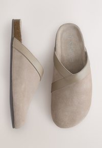 Chaussures slip-on beige clair avec texture en daim et une bride lisse diagonale, semelle plate, vues de dessus et de côté.