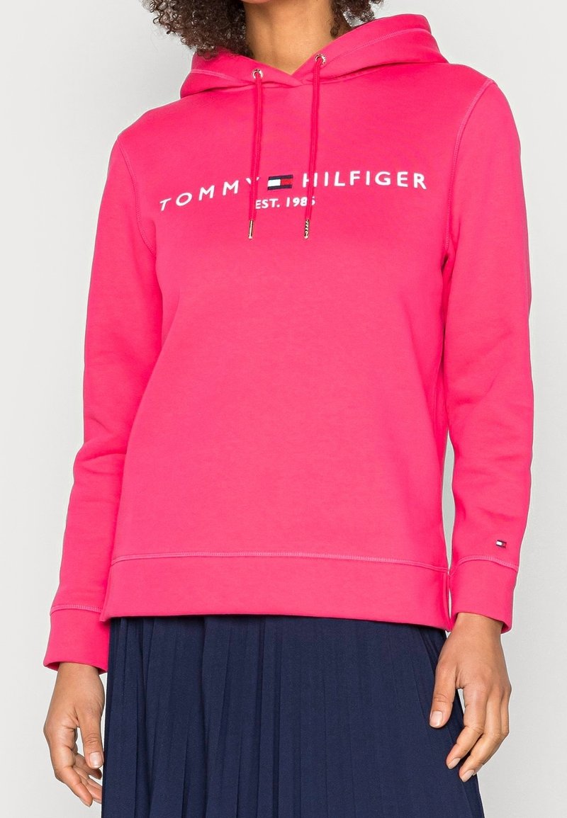 Felpa a collo alto rosa con lacci, caratterizzata dal logo bianco "TOMMY HILFIGER EST. 1985". Maniche lunghe e orlo a coste. Tessuto morbido.