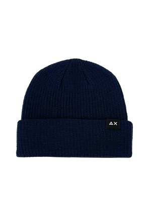 Beanie lavorato a maglia di colore blu navy con una texture a coste e un risvolto. Presenta un'etichetta nera con un design geometrico bianco sul lato.