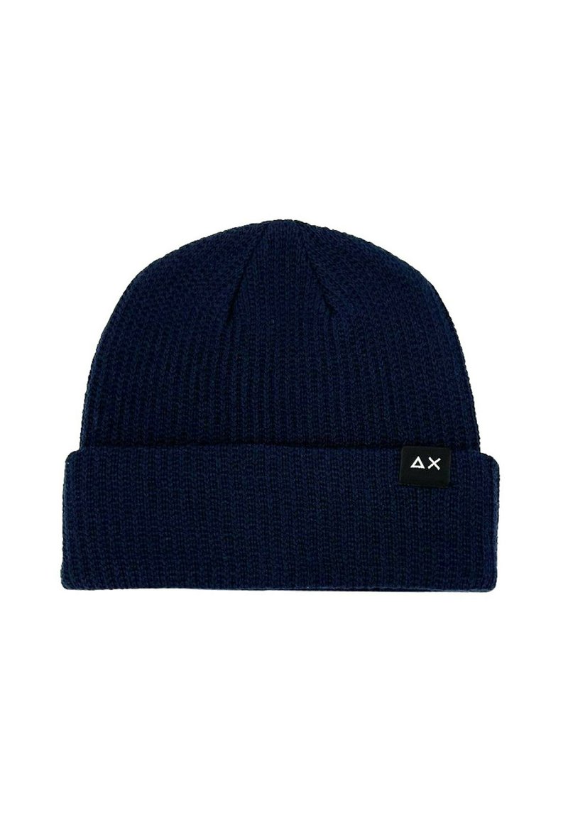 Beanie lavorato a maglia di colore blu navy con una texture a coste e un risvolto. Presenta un'etichetta nera con un design geometrico bianco sul lato.