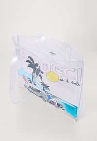 Sac fourre-tout en PVC transparent avec impression graphique, présentant des palmiers, un soleil et une voiture vintage. Éléments bleu et logo en haut.