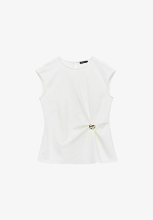 Biała krótka bluzka z krótkim rękawem i okrągłym dekoltem, z twistem w okolicy talii oraz dekoracyjnym srebrnym guzikiem. Gładka tekstura materiału.