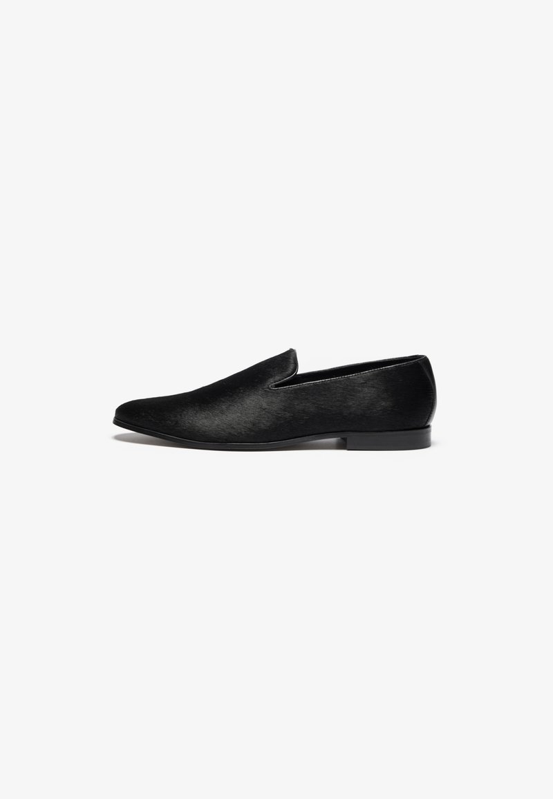 Black slip-on shoe in smooth material with a slightly pointed toe and low heel, featuring a simple design and sleek finish.
