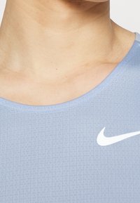 Light blue athletic shirt with a round neckline, textured fabric, and a white Nike logo on the left side.