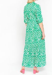 Grön och vit lång klänning med leopardmönster, puffärmar, åtdragen midja och lagerkjol. Matchad med rosa blockklackssandaler.