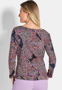 Langarmtop met een donkere achtergrond en een levendig bloemenpatroon in roze, paars en blauw. Zachte stof met een ontspannen pasvorm.