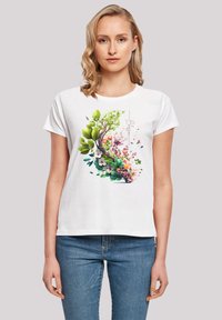 White cotton t-shirt featuring a vibrant floral design with green leaves, pink flowers, and a brown branch, short sleeves, and a round neckline.
