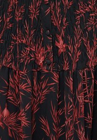 Robe noire avec imprimé botanique rouge, présentant une texture froncée, des accents de boutons et une coupe fluide. Tissu doux avec une taille froncée.
