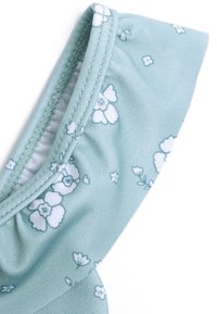 Tessuto azzurro chiaro con motivi floreali bianchi, con dettagli arricciati lungo il bordo e una consistenza liscia.