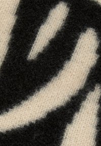 Motivo astratto in nero e crema con fibre testurizzate su uno sfondo di tessuto intrecciato. Linee audaci e fluide creano un contrasto visivo.