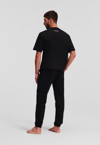 Schwarzes Baumwoll-T-Shirt und -Hosen-Set mit Rundhalsausschnitt und lockerer Passform. Einfaches Design ohne sichtbare Muster oder Verzierungen.