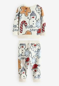 Ensemble de pyjama en polaire avec une base crème, présentant des motifs colorés de bonhommes de neige, de biscuits en pain d'épice et de cannes en sucre. Comprend des poignets côtelés.