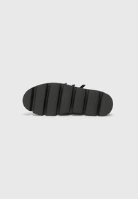 Black shoe sole with a textured finish, featuring ridged pattern and rounded edges. No visible branding or accents.