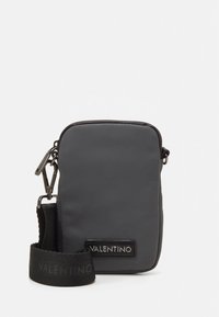 Kompakt svart axelväska med strukturerad yta, märkt Valentino-märke och justerbar rem med metallspännen.