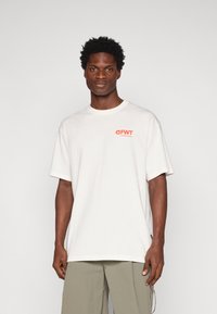 Λευκό κοντομάνικο μπλουζάκι με στρογγυλή λαιμόκοψη, που διαθέτει το κόκκινο λογότυπο "FWT" στην αριστερή πλευρά του στήθους. Μαλακό βαμβακερό ύφασμα, χαλαρή εφαρμογή.