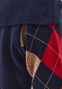Maglione blu navy con collo a coste e motivo argyle in rosso, beige e blu navy. Texture morbida con maniche a contrasto.