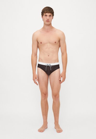 Schwarze Schwimm-Badehose mit einem weißen Bund, ausgestattet mit einem Kordelzug. Der Stoff sieht glatt und enganliegend aus und bietet minimalen Schutz.