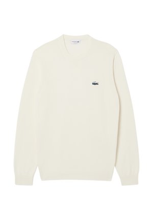 Suéter de color crema con un escote redondo y puños acanalados. Presenta un pequeño logo de Lacoste en azul y verde en el lado izquierdo del pecho.