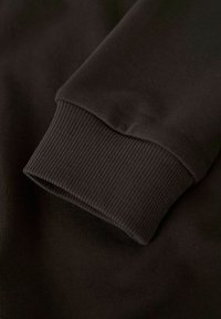 Puño de sudadera de color marrón oscuro con textura suave y un ajuste entallado, que muestra costuras uniformes y sin logotipos o patrones visibles.