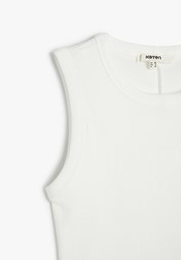 Débardeur en coton blanc sans manches, avec un col arrondi. Fabriqué à partir de coton avec une texture lisse. L'étiquette indique la taille medium et la marque "Koton."