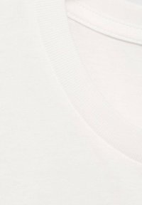 Bílý bavlněný tričko s žebrovaným kulatým výstřihem. Materiál vypadá jemně s hladkým povrchem a ukazuje jednoduchý, klasický design.