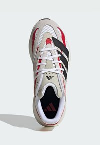 Adidas tenisice s bež, crnom i crvenom dizajnom. Izrađene su od mrežice i antilopa, imaju zaobljen vrh i bijele vezice s logotipom na ulošku.