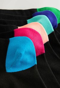 Čierne ponožky s jasne farebnými špičkami v modrej, ružovej, broskyňovej, tyrkysovej, fialovej a zelenej farbe zoradené v rade.