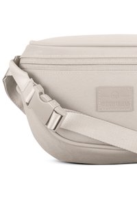 Beige sling táska texturált anyagból, cipzáras záródással és állítható pánttal, amely műanyag csattal és logópatch-rel rendelkezik.