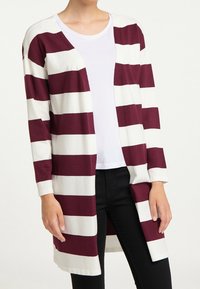 Maroon and white striped cardigan with long sleeves, open front, and a slightly textured fabric. Paired with a white T-shirt and black pants.