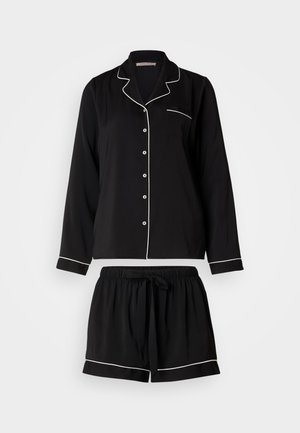 Black pajama set includes a button-up long-sleeve top with white piping and a pocket, paired with matching drawstring shorts.