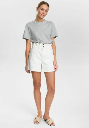 Grijze T-shirt, witte high-waisted shorts met knoopdetail aan de voorkant en zakken, gecombineerd met beige instap schoenen. Glad stof, schoon ontwerp.