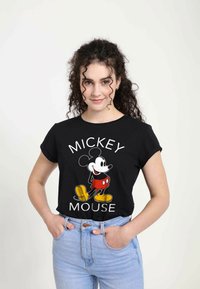 Černé bavlněné tričko s barevným potiskem Mickey Mouse. Výstřih je kulatý s ohrnutými rukávy. Kombinováno se světle modrými džíny.