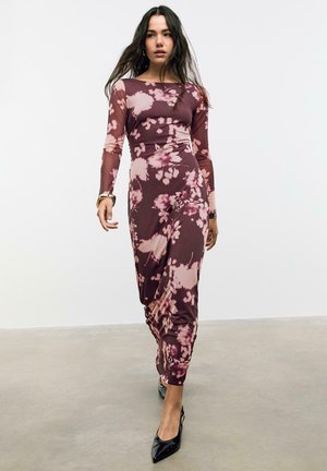 Pitkähihainen, slim fit -mekko burgundinpunaisena, jossa on vaaleanpunaisia kukkakuoseja. Pehmeä, joustava kangas, jossa on laskostettu rakenne. Mustat teräväkärkiset korkokengät.