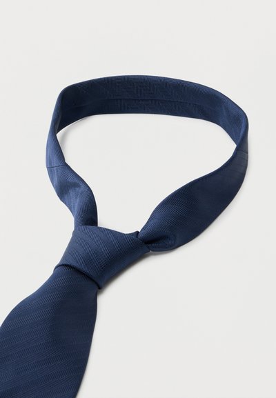 Γραβάτα σε ναυτικό μπλε χρώμα με διακριτικό σχέδιο ψαροκόκκαλο, μερικώς δεμένη, παρουσιάζεται σε λευκό φόντο.