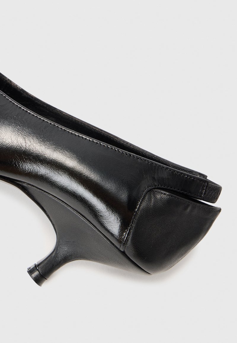 Schwarzer Lederhochschuh mit einem eleganten Design, abgerundetem Zehenbereich, glatter Oberfläche und einem schmalen Absatz. Dezente Nähte sind sichtbar.