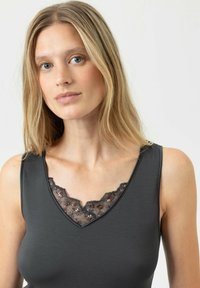 Canotta grigia scura con scollatura a V, caratterizzata da un bordo in pizzo nero decorativo accentuato da piccoli motivi floreali in colori tenui.