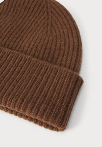 Καφέ ριμπ πλεκτό σκουφάκι με αναδιπλούμενο γείσο. Φτιαγμένο από μαλακό υλικό, διαθέτει υφή και εφαρμοστό σχήμα.