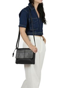 Borsa a tracolla in pelle nera con patta frontale, logo embossato e cuciture semplici. Texture liscia e forma rettangolare.